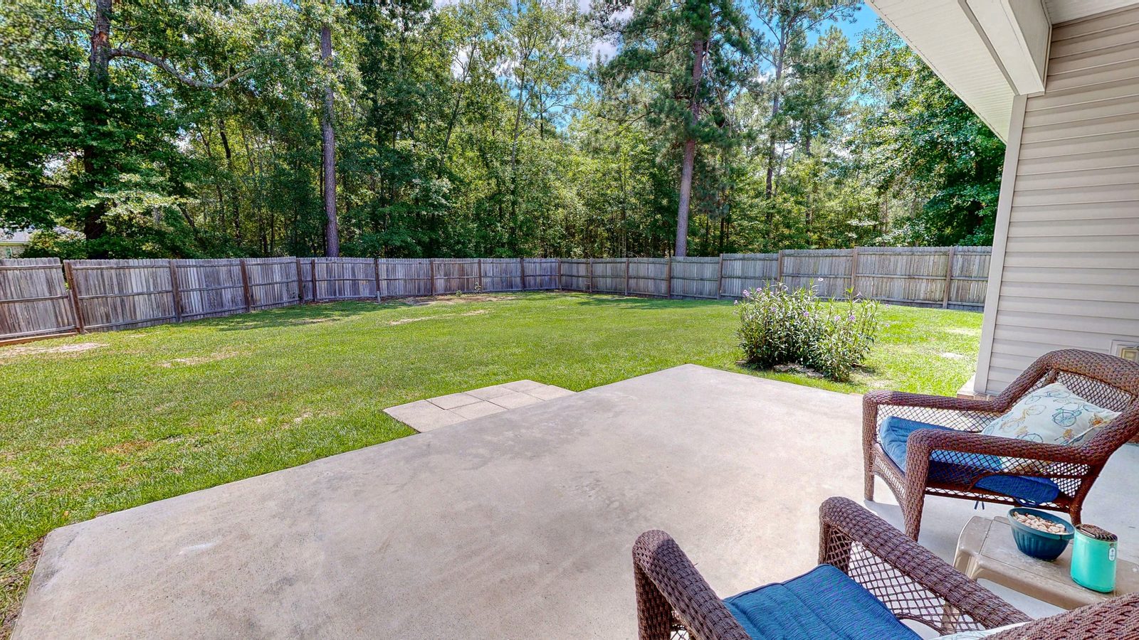 Fenced backyard and covered porch on the wooded acre at 505 Trinity Ave, Brooklet